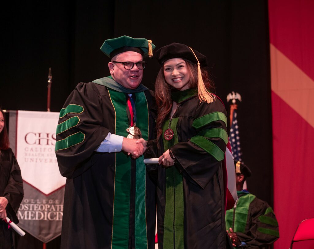 dean and graduate in regalia holding diploma