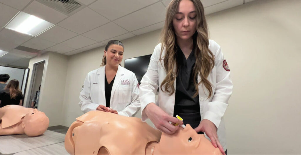 Women administering nasal spray to manikin trainer