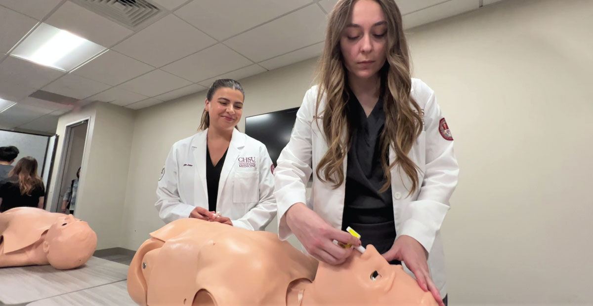 Women administering nasal spray to manikin trainer