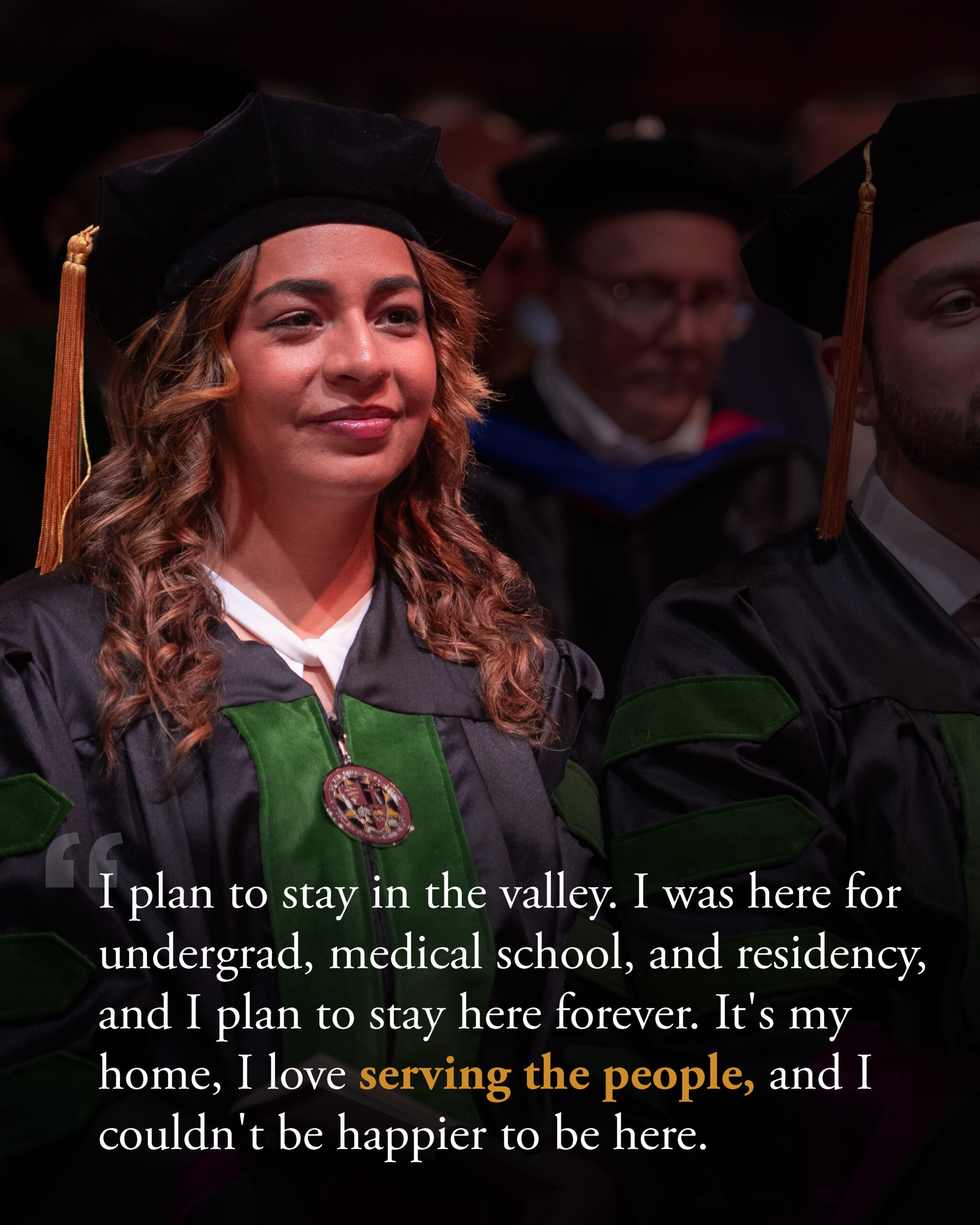 female wearing graduate regalia with other graduates in background