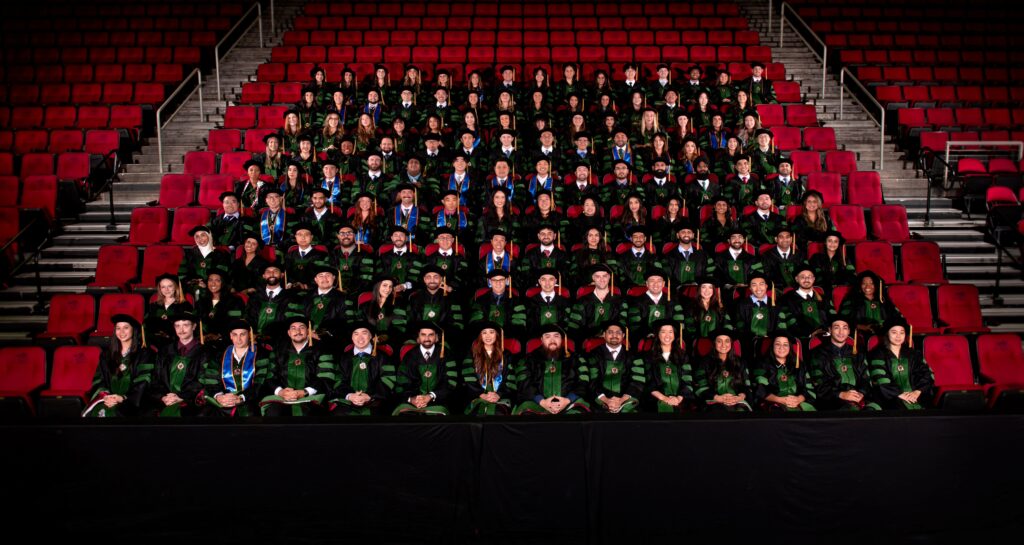 group photo of 2026 DO graduates wearing regalia seated in stands