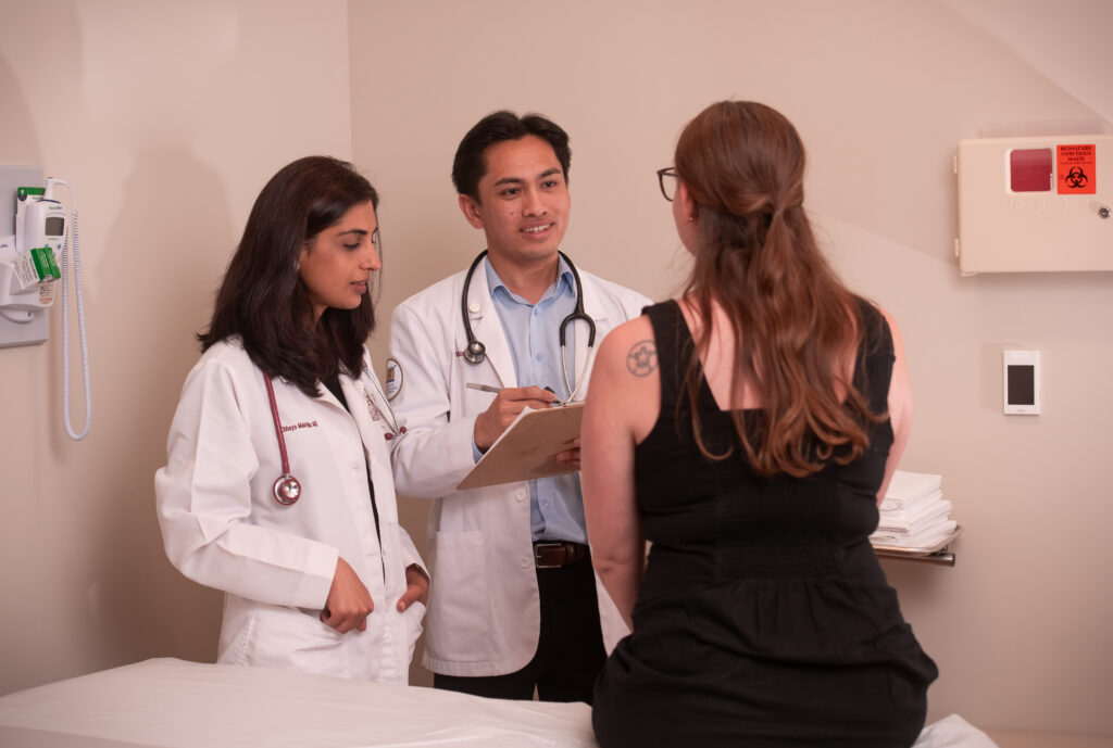 physician overseeing medical student questioning standardized participant in office