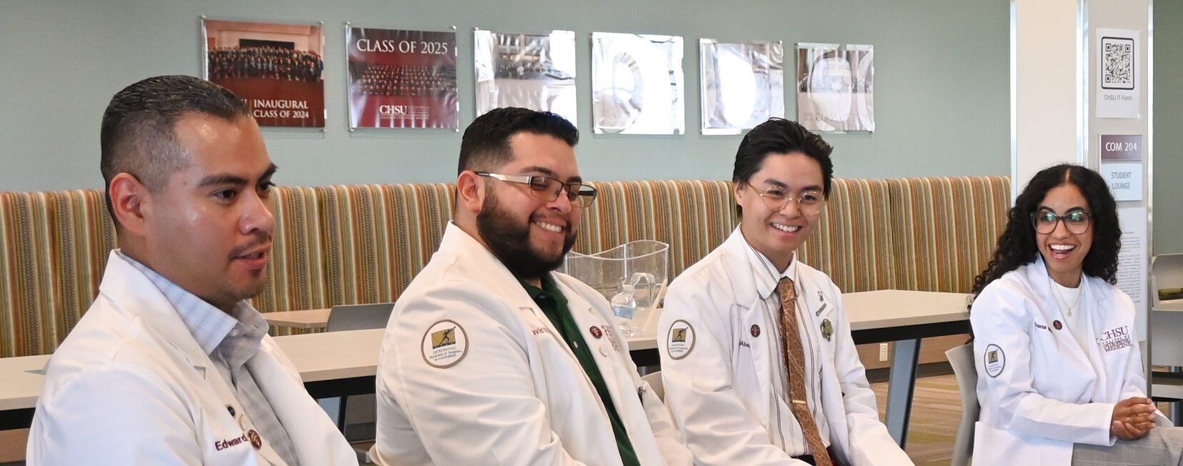 Five CHSU College of Osteopathic Medicine students in white coats participate in a group discussion with prospective medical students.
