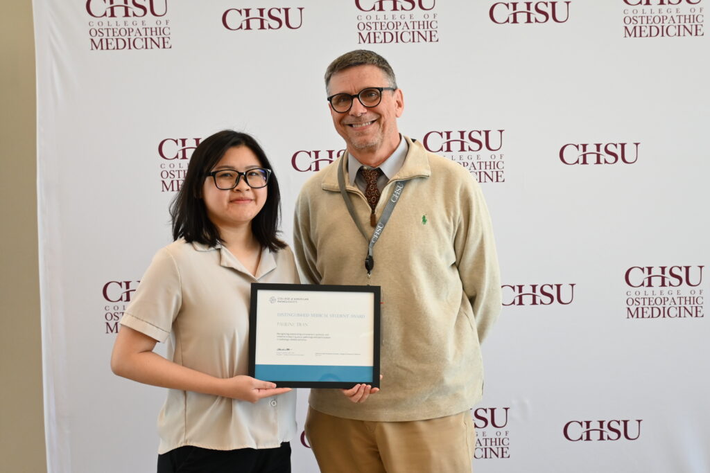 Person holding award with faculty member