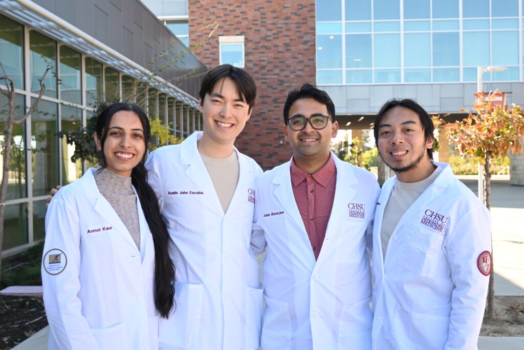 students wearing white coats standing in front of building