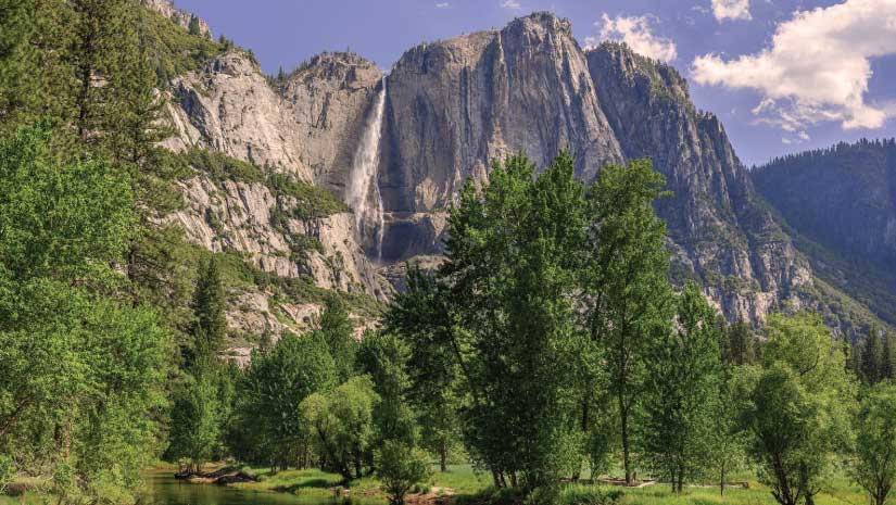 Yosemite Falls granite mountain with large waterfall and trees at base