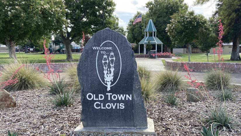 Welcome to Old Town Clovis stone monument in park with gazebo American flag trees and grass