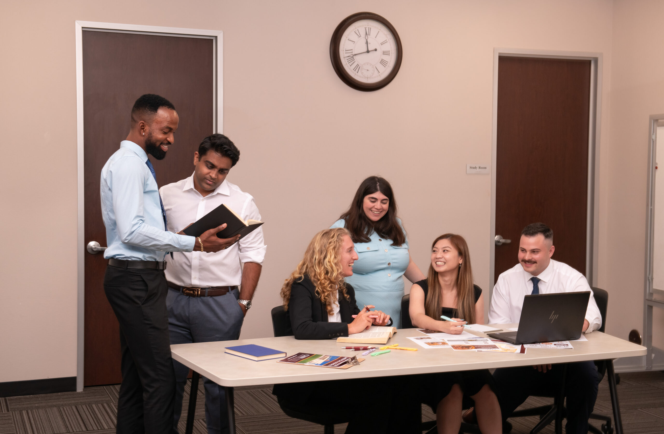 students seated at table and standing behind table studying together