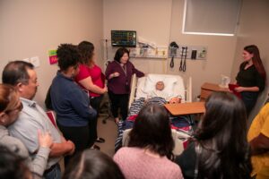 Simulated hospital room with child maniken in bed and group gathered around