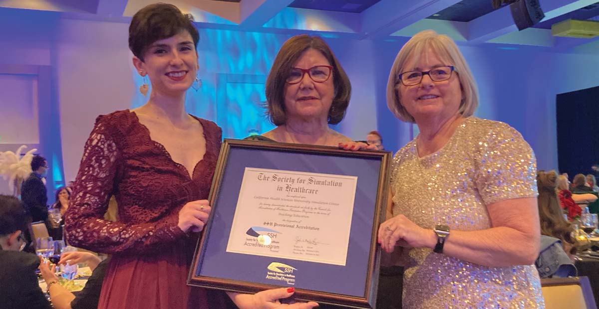 Three women holding a framed certificate.